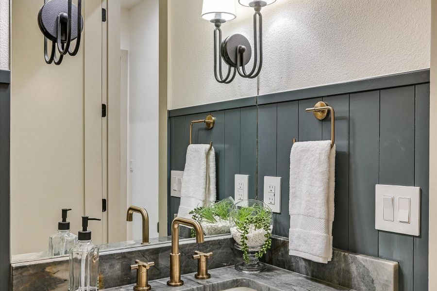 Beautiful natural stone vanity and champagne bronze fixtures create a luxurious feel in this well-appointed powder room that will impress your guests! Beautiful natural stone vanity and champagne bronze fixtures create a luxurious feel in this well-appointed powder room that will impress your guests!