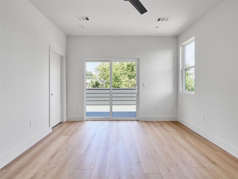 Unfurnished room featuring healthy amount of natural light, light wood-type flooring, and ceiling fan Unfurnished room featuring healthy amount of natural light, light wood-type flooring, and ceiling fan