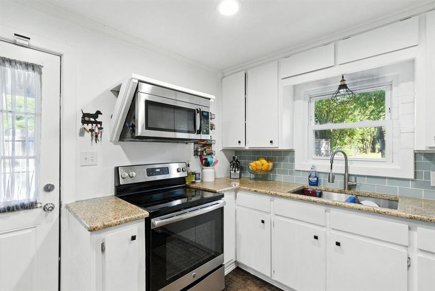 Kitchen featuring appliances with stainless steel finishes, healthy amount of natural light, white cabinets, and ornamental molding