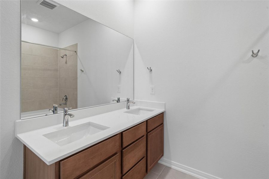 Luxurious primary suite bath boasts a large vanity with double sinks, topped with elegant countertops.
