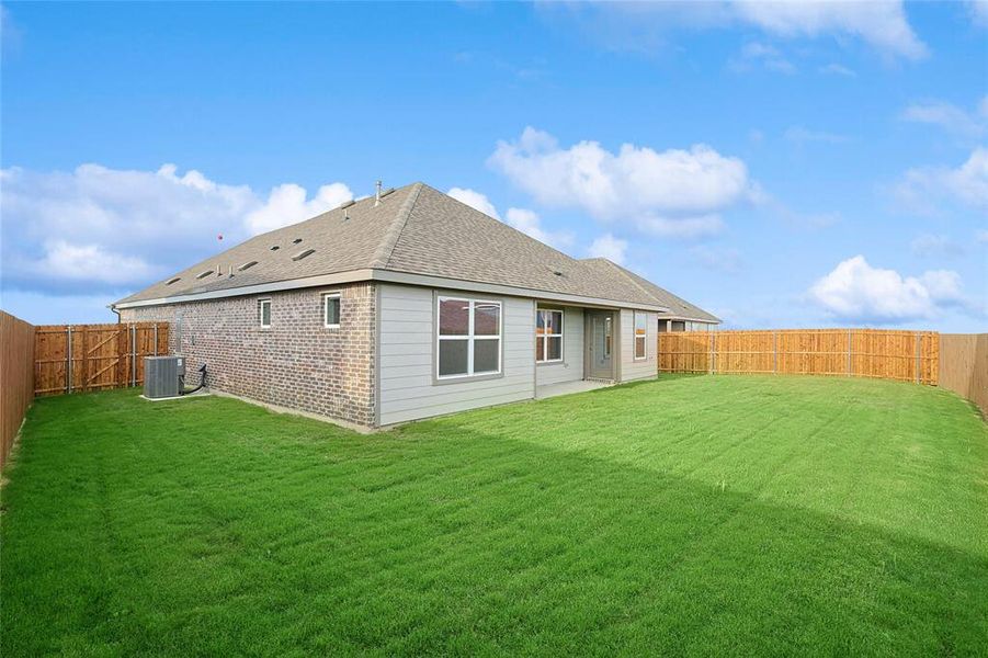 Rear view of house with central AC unit and a lawn