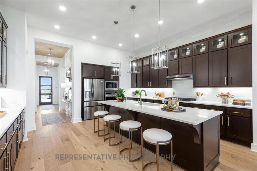 Kitchen featuring dark brown cabinets, decorative backsplash, a kitchen breakfast bar, recessed lighting, and light wood-type flooring