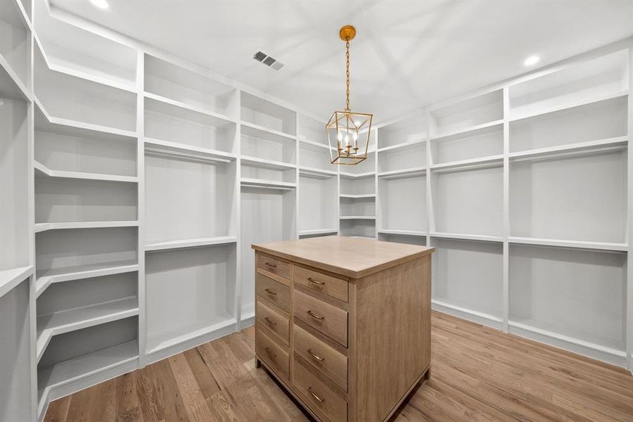 Spacious walk-in closet featuring extensive built-in shelving, hanging rods, and a central island with drawers