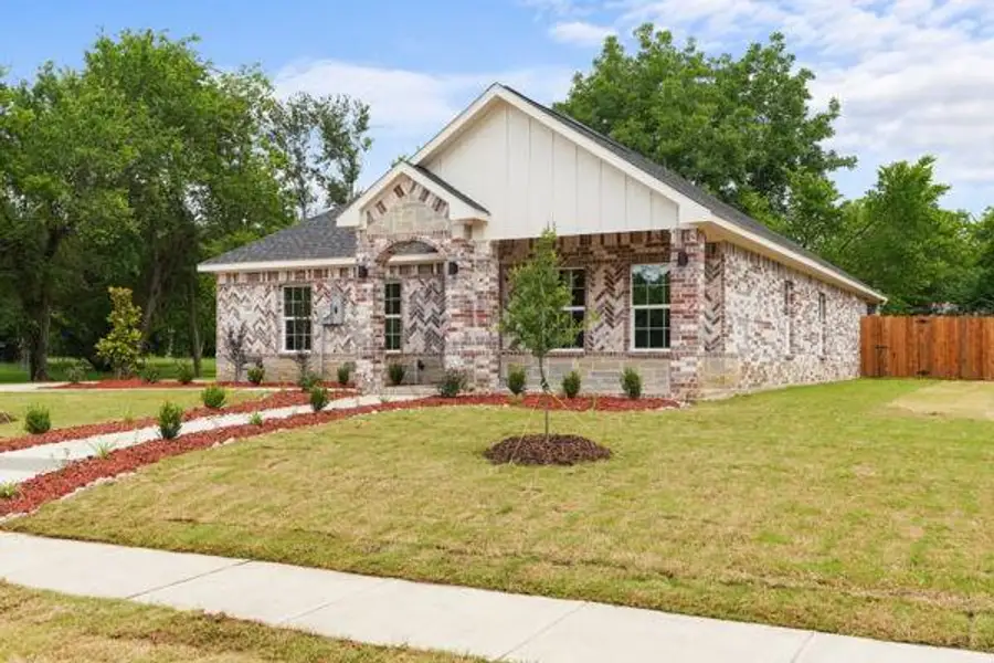 Exterior featuring varied brick patterns, a white vertical siding gable, a covered entry porch, a side yard with a wooden privacy fence, and a concrete sidewalk with a landscaped border Exterior featuring varied brick patterns, a white vertical siding gable, a covered entry porch, a side yard with a wooden privacy fence, and a concrete sidewalk with a landscaped border