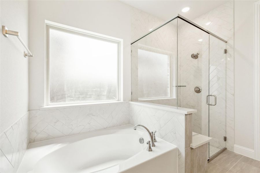 Master bathroom with soaking tub, glass-enclosed shower, and white herringbone tile walls