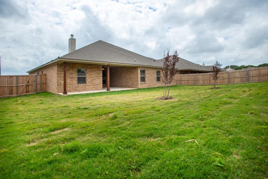 Rear view of house with a lawn, a patio, a chimney, and a fenced backyard