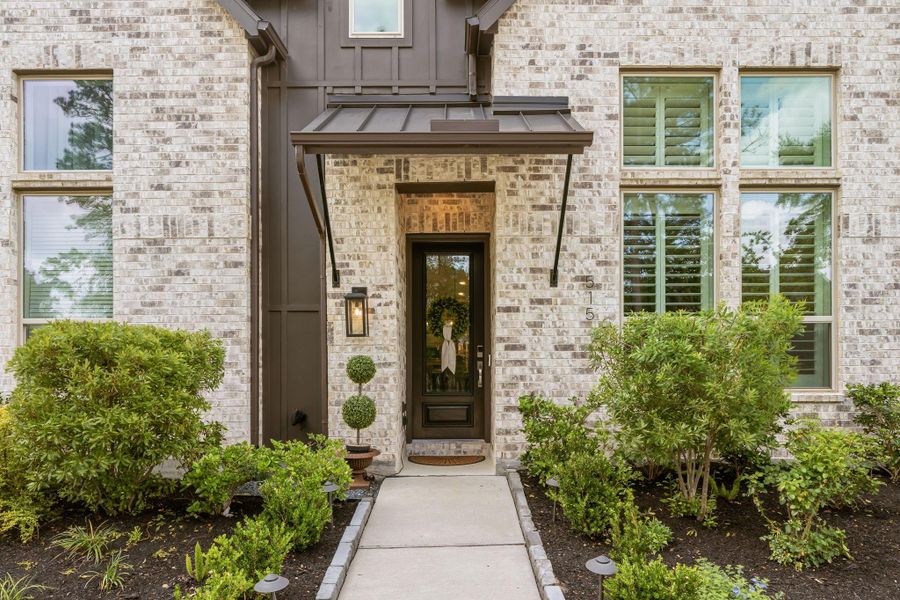 Gorgeous front entry includes landscape lighting and beautiful glass door for views of the green space -