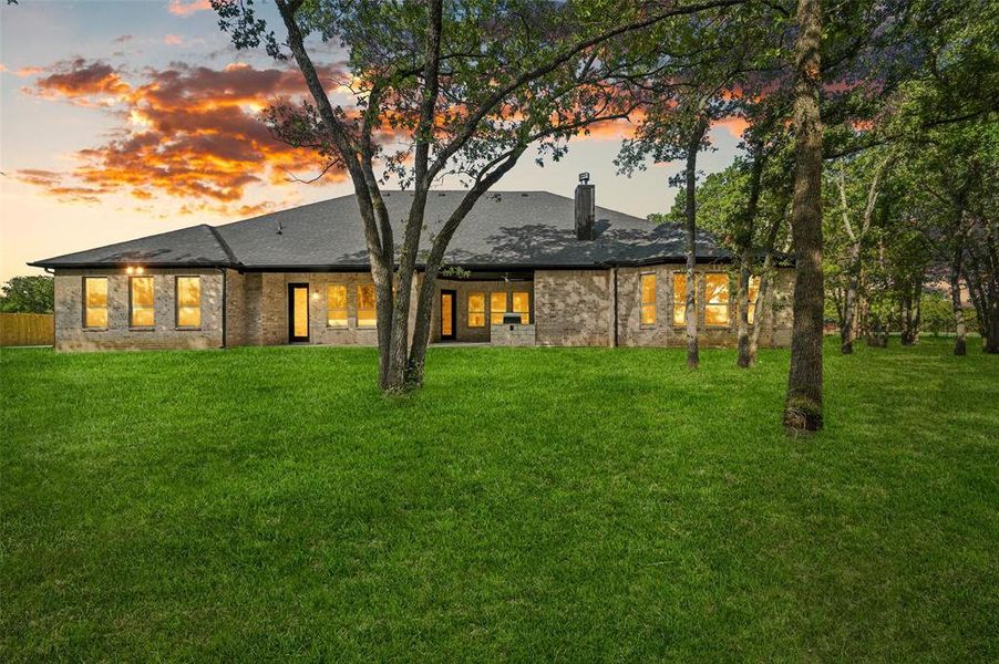 Back house at dusk featuring a yard