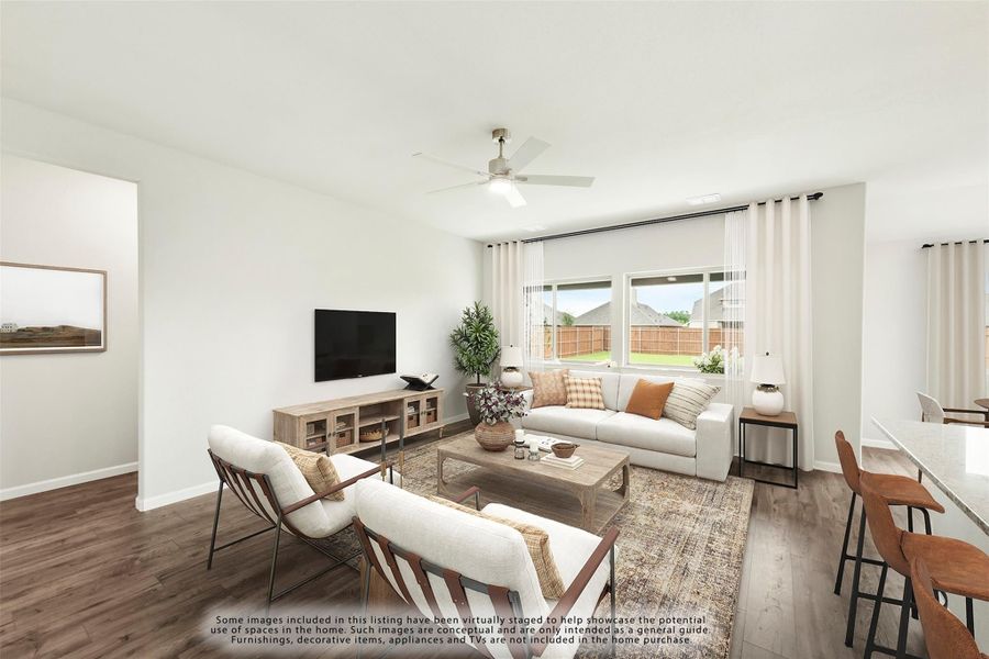 Open living room with hardwood floors, ceiling fan, large windows, and neutral furniture with backyard view