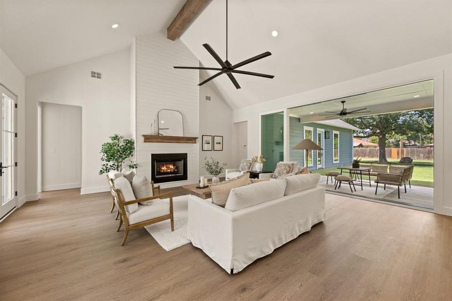 Living area featuring beamed ceiling, a fireplace, high vaulted ceiling, light wood-style flooring, and recessed lighting Living area featuring beamed ceiling, a fireplace, high vaulted ceiling, light wood-style flooring, and recessed lighting
