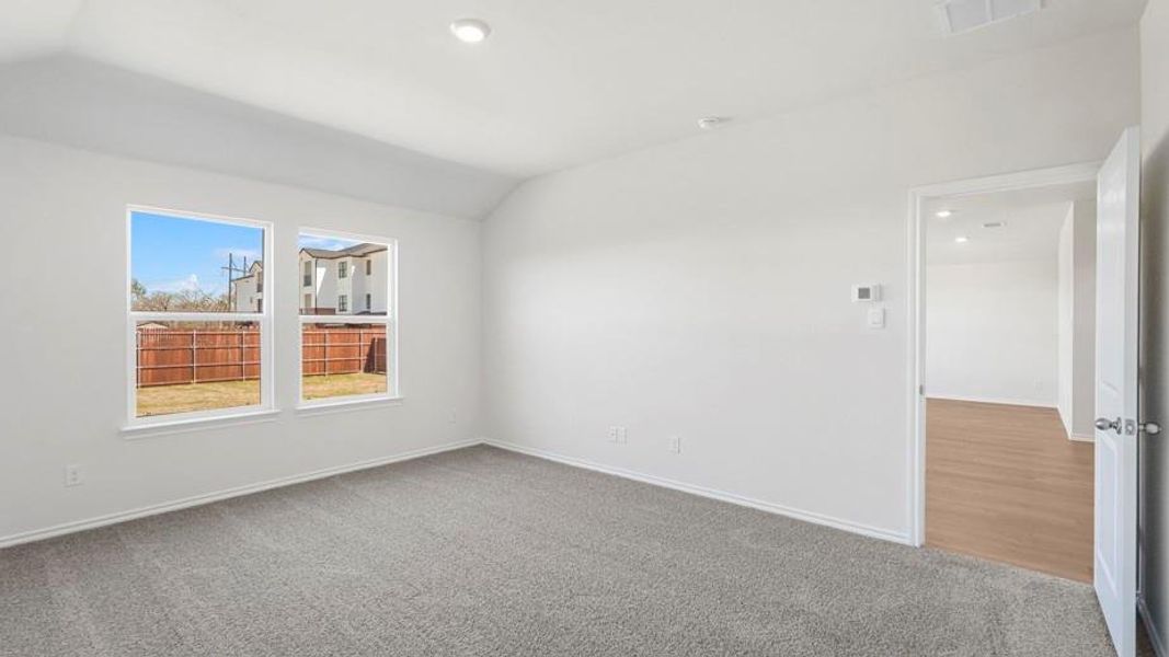 Spacious room featuring two large windows, vaulted ceiling, recessed lighting, and soft grey carpeting
