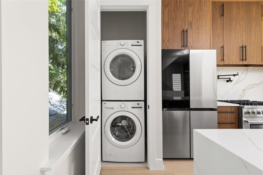 In-unit laundry facilities sit directly adjacent to a modern kitchen with sleek cabinetry.