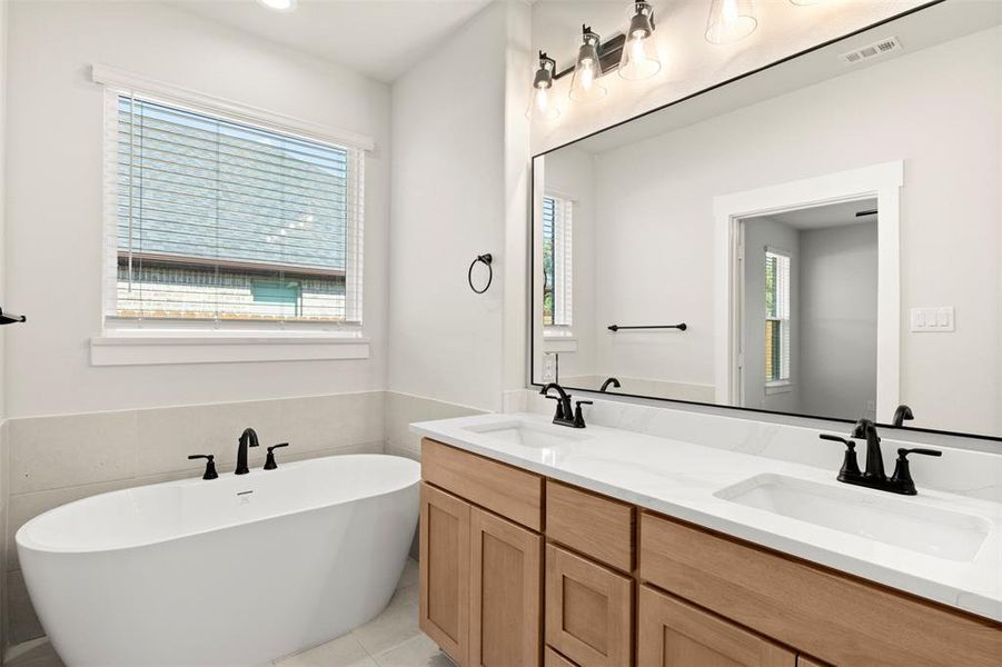 Full bathroom with a soaking tub, double vanity, and tile walls