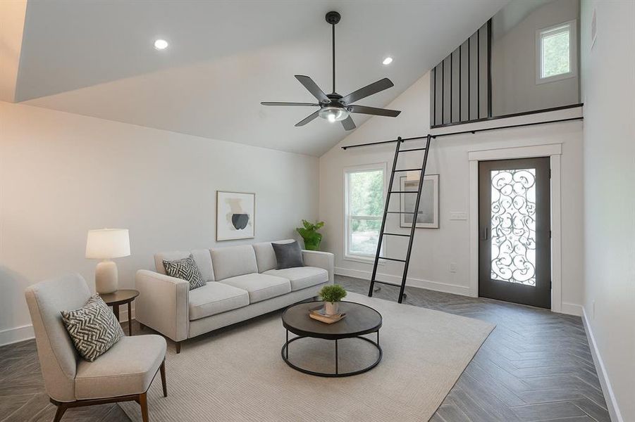 Living area with high vaulted ceiling, a barn door, ceiling fan, and recessed lighting Living area with high vaulted ceiling, a barn door, ceiling fan, and recessed lighting