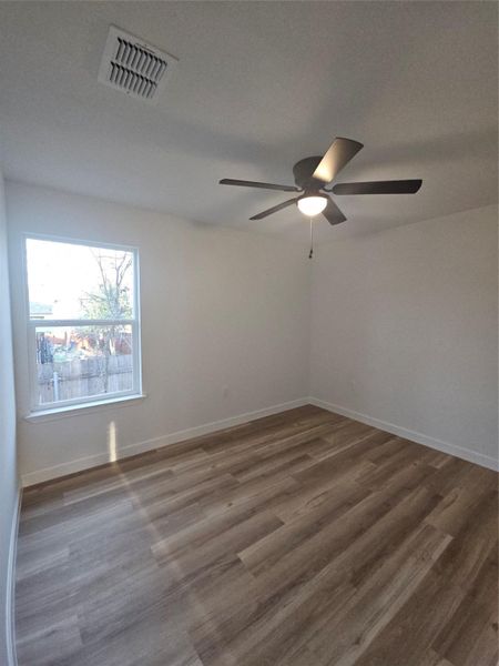 Spare room featuring a ceiling fan, wood finished floors, visible vents, and baseboards