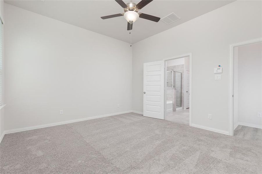 Unfurnished bedroom featuring light colored carpet, connected bathroom, and ceiling fan