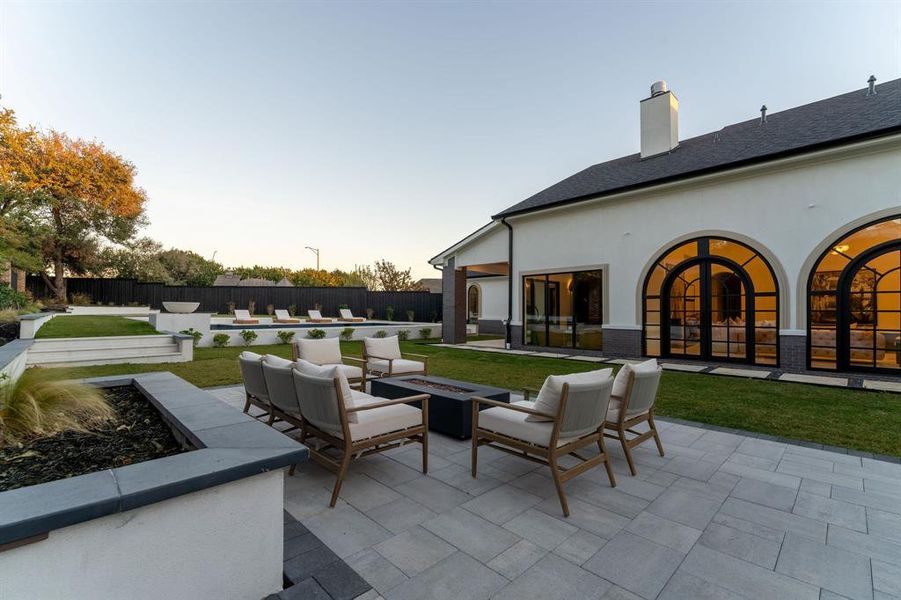 Fenced backyard featuring a patio area and an outdoor living space with a fire pit