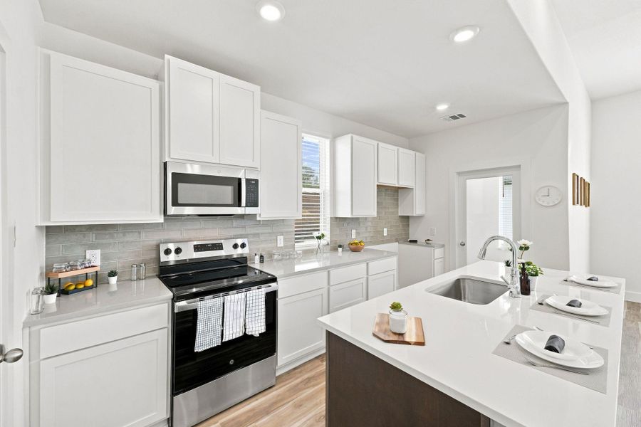 Modern kitchen featuring abundant cabinetry, quartz countertops, stainless steel appliances, and a stylish tile backsplash. Modern kitchen featuring abundant cabinetry, quartz countertops, stainless steel appliances, and a stylish tile backsplash.