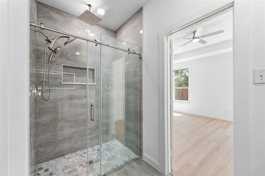 Modern glass-enclosed shower with a rainfall showerhead, handheld sprayer, and tiled walls