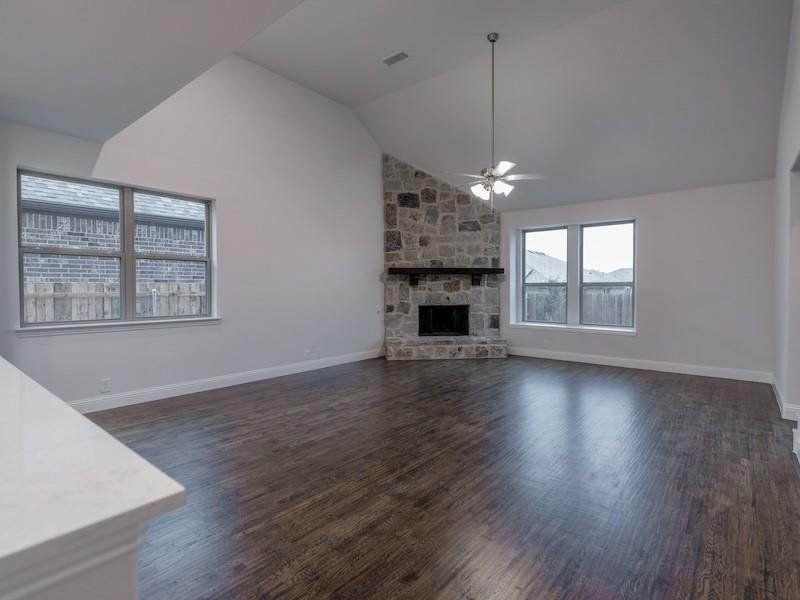 Unfurnished living room with a fireplace, dark wood-type flooring, vaulted ceiling, and ceiling fan