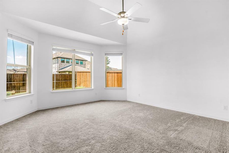 Spacious room with a vaulted ceiling, light gray carpeting, and white walls