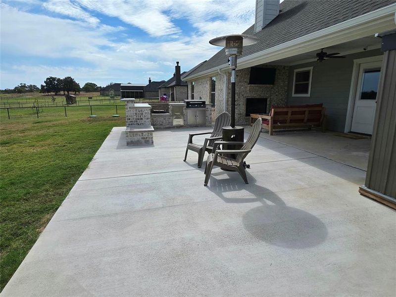 View of patio / terrace featuring exterior kitchen, ceiling fan, and a large fireplace