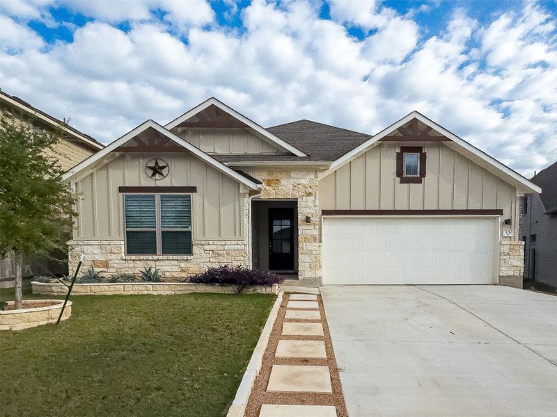 View of front of home featuring board and batten siding, stone siding, driveway, and a front yard View of front of home featuring board and batten siding, stone siding, driveway, and a front yard