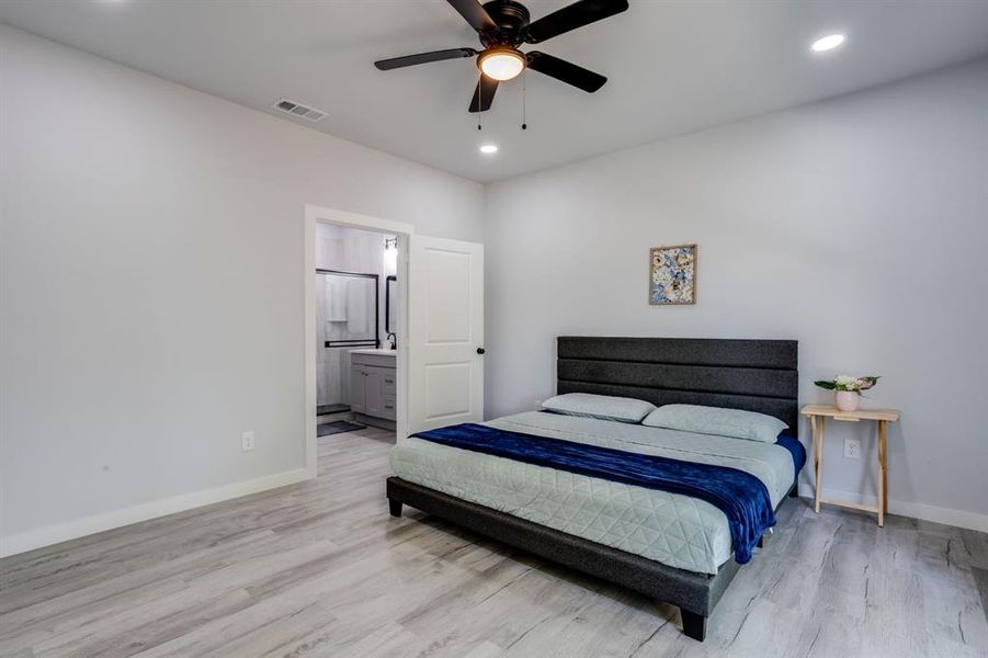 Bedroom with light wood finished floors, recessed lighting, ensuite bathroom, and a ceiling fan Bedroom with light wood finished floors, recessed lighting, ensuite bathroom, and a ceiling fan
