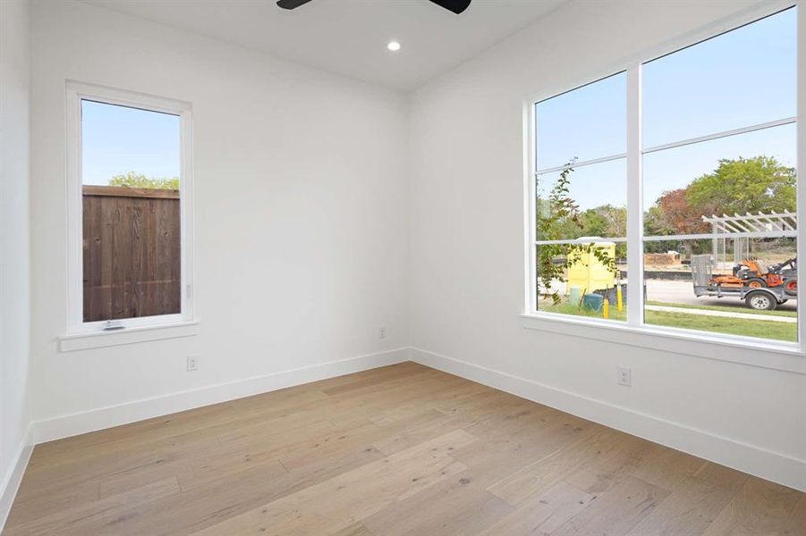 Unfurnished room featuring light hardwood / wood-style floors, ceiling fan, and a wealth of natural light