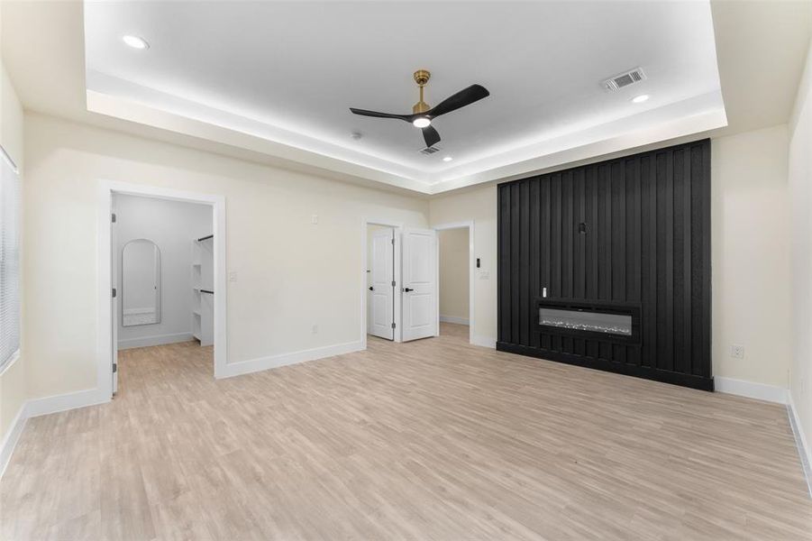 Unfurnished bedroom featuring recessed lighting, a raised ceiling, light wood-style floors, and a ceiling fan