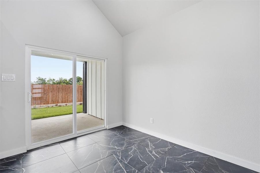 Sliding glass doors opening to a concrete patio and a private backyard with a wood fence