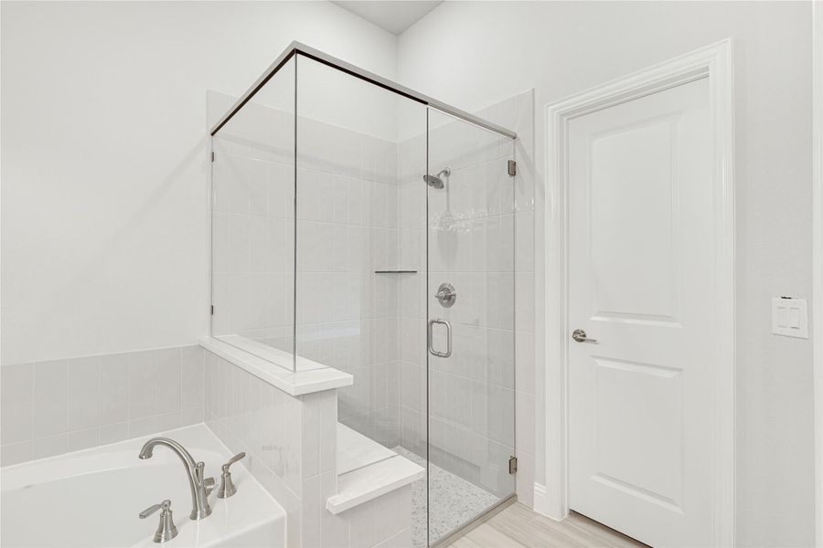 Bathroom with glass-enclosed walk-in shower, white tile walls, and soaking tub with chrome faucet