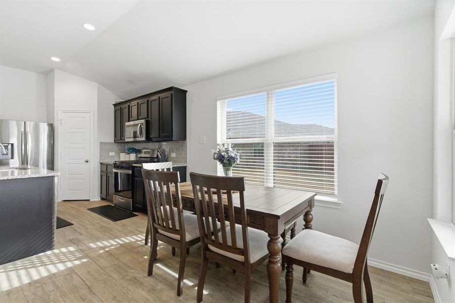 Dining area with light wood-type flooring, lofted ceiling, and recessed lighting