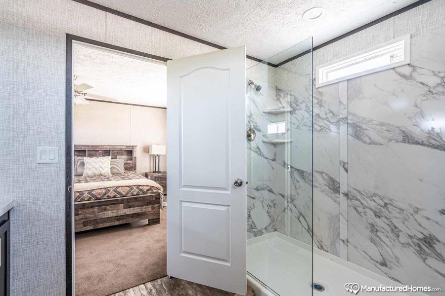 A well-appointed bathroom offers a spacious walk-in shower with elegant marble-patterned walls and glass enclosure.