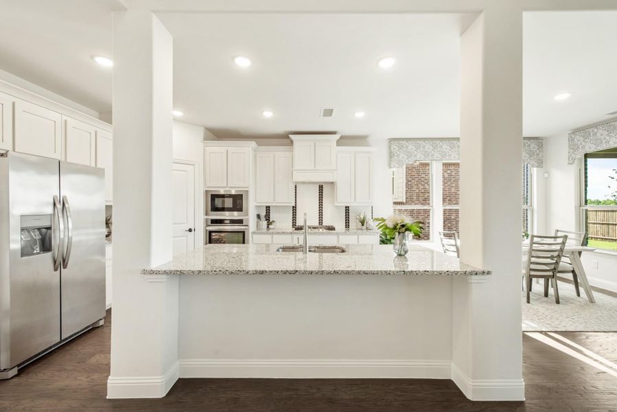 Open kitchen with white cabinets, granite island, stainless appliances, and dark hardwood floors
