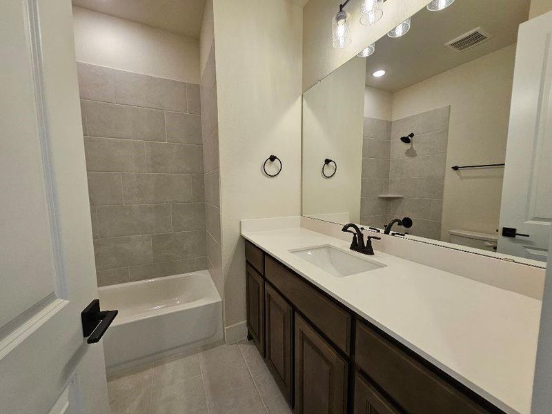 Bathroom featuring vanity, light tile patterned flooring, and shower / tub combination