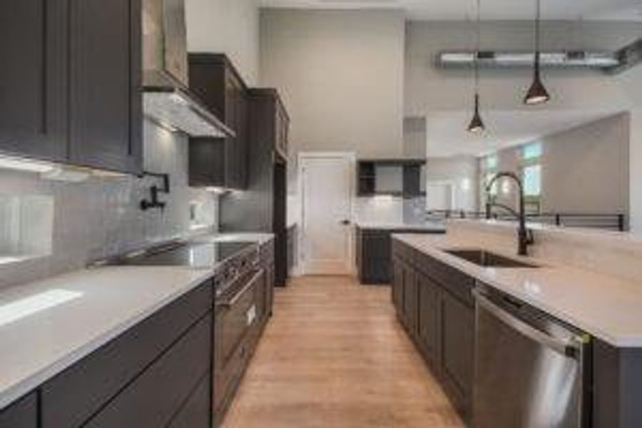 Kitchen with a sink, light countertops, appliances with stainless steel finishes, decorative light fixtures, and light wood-type flooring