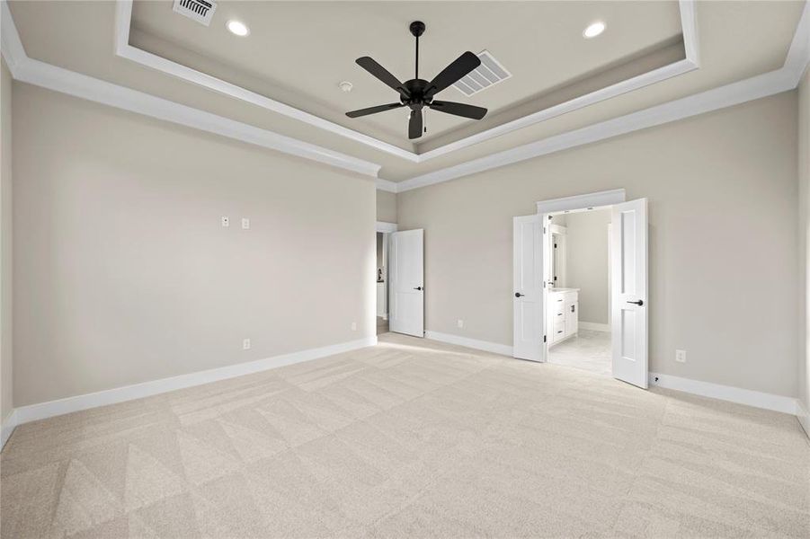 Unfurnished bedroom with a tray ceiling, light colored carpet, crown molding, a ceiling fan, and recessed lighting