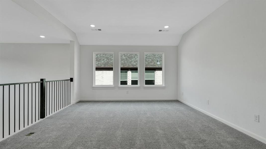 Carpeted empty room featuring lofted ceiling