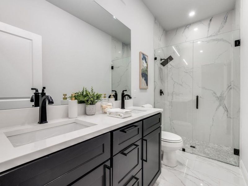 2nd Bathroom featuring light marble finish flooring, double vanity, and a marble finish shower.