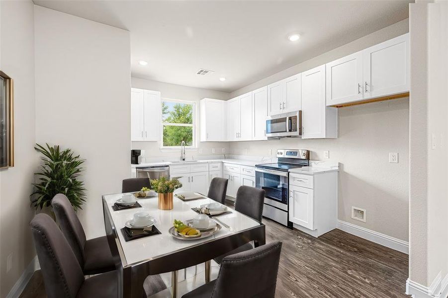 Kitchen with dark hardwood / wood-style floors, stainless steel appliances, white cabinets, and sink