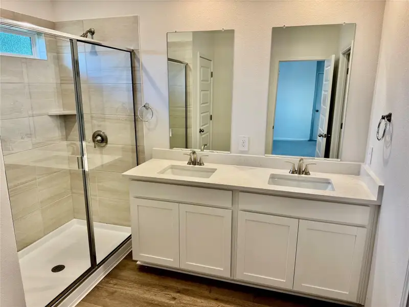 Bathroom with a shower stall, double vanity, and dark wood finished floors Bathroom with a shower stall, double vanity, and dark wood finished floors