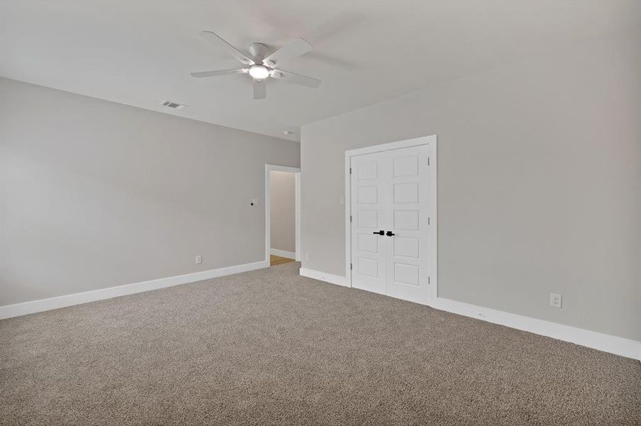Carpeted spare room with a ceiling fan and baseboards Carpeted spare room with a ceiling fan and baseboards