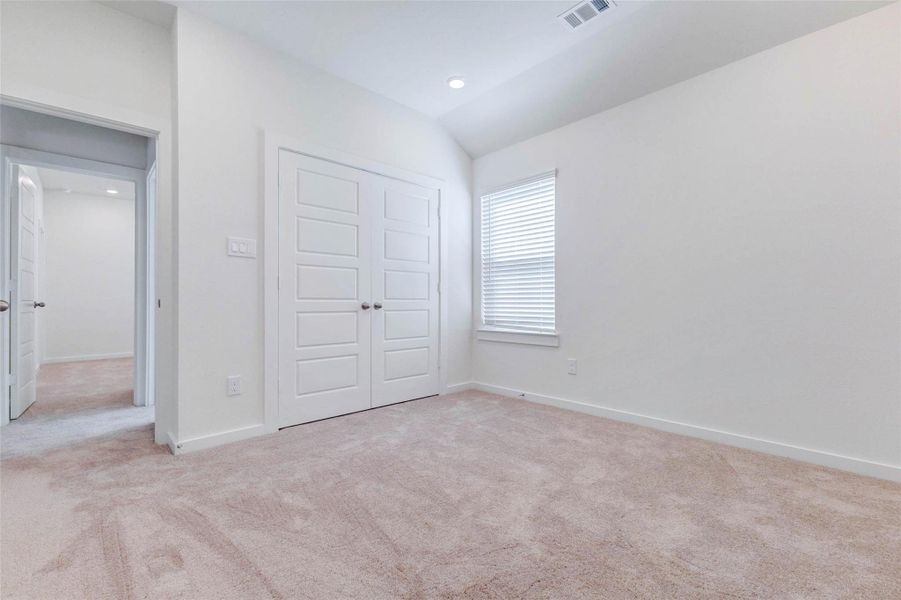 Secondary bedroom with soft carpet, high ceiling, window with blinds, double-door closet, and neutral walls. The room offers flexible use as a guest room, child’s room, home office, nursery, or hobby space, with bright natural light and an easy-to-personalize layout.