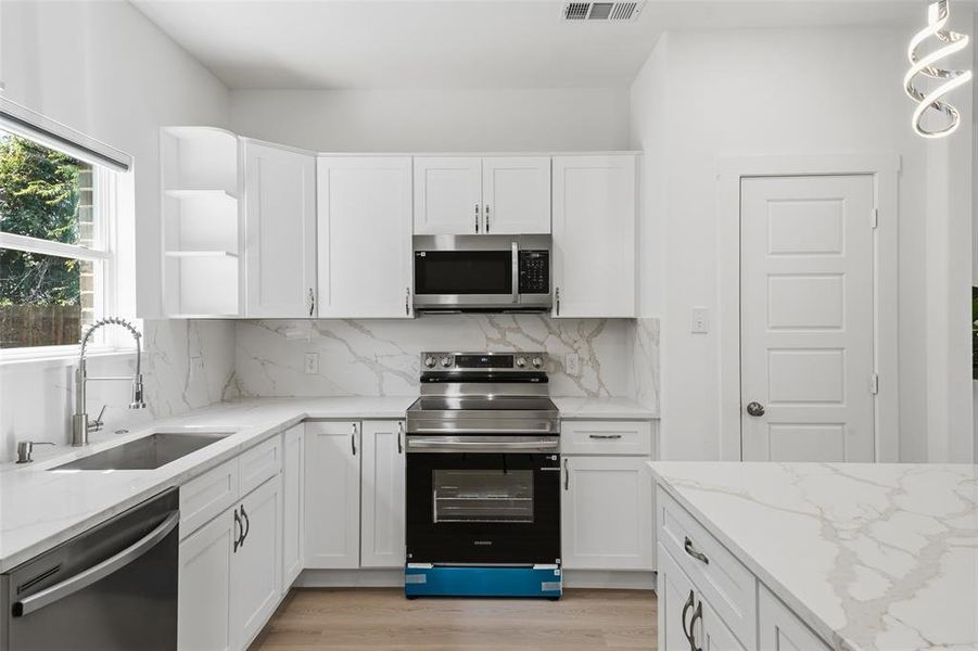 Modern kitchen featuring white shaker cabinetry and integrated stainless steel appliances