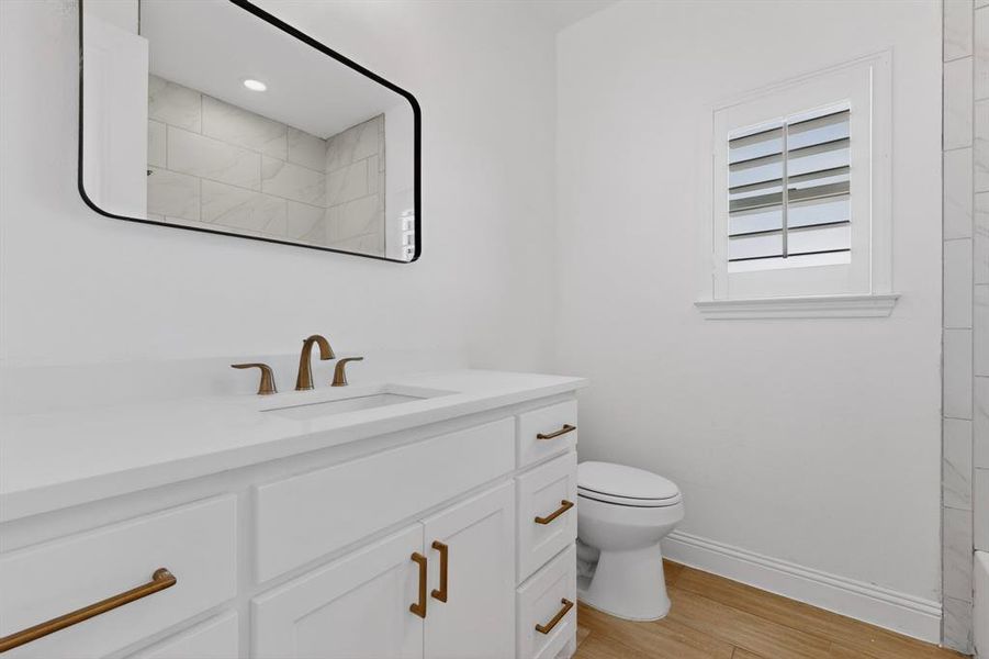 Bathroom vanity with a white countertop and integrated sink, bronze-finish faucet, and coordinating cabinet hardware Bathroom vanity with a white countertop and integrated sink, bronze-finish faucet, and coordinating cabinet hardware