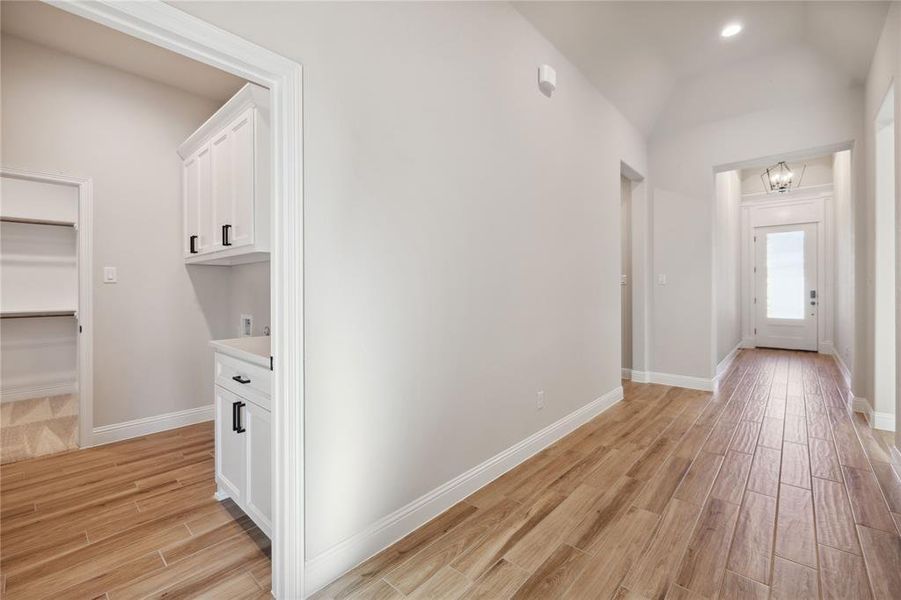 Corridor featuring lofted ceiling and an inviting chandelier