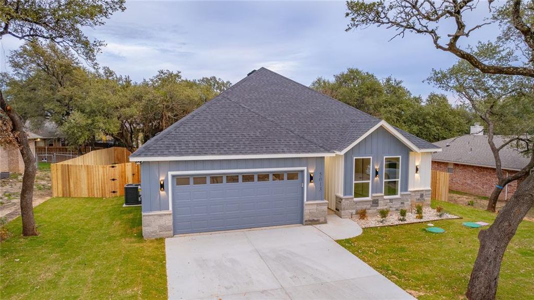 View of front of property featuring a front lawn, cooling unit, and a garage