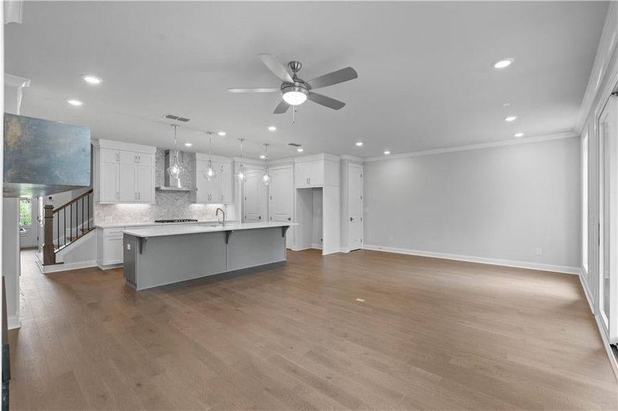 Unfurnished living room with dark wood-style floors, ceiling fan, stairway, recessed lighting, and crown molding Unfurnished living room with dark wood-style floors, ceiling fan, stairway, recessed lighting, and crown molding