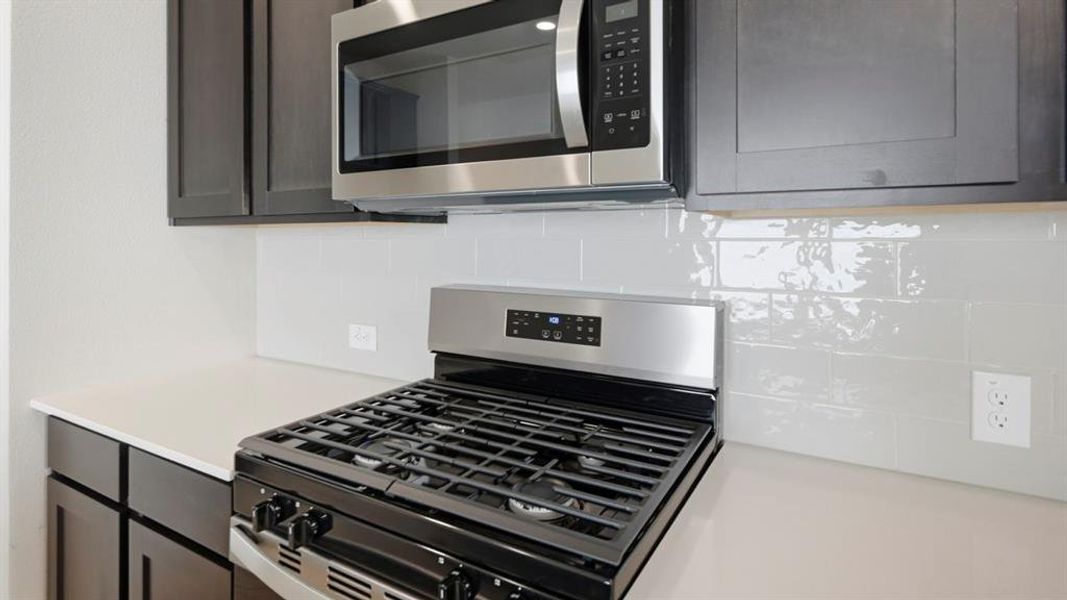 Kitchen with appliances with stainless steel finishes and decorative backsplash